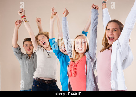 Ritratto di un gruppo di ragazzi adolescenti e le ragazze con le braccia in aria, sorridente e guardando la telecamera, Studio shot su sfondo bianco Foto Stock