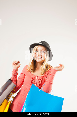 Ritratto di bionda, la ragazza con i capelli dritti, tenendo le borse della spesa e sorridente alla fotocamera, Studio shot su sfondo bianco Foto Stock