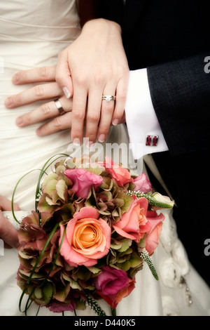 Dettaglio della sposa e lo sposo che mostra le mani, anelli e sposa bouquet Foto Stock