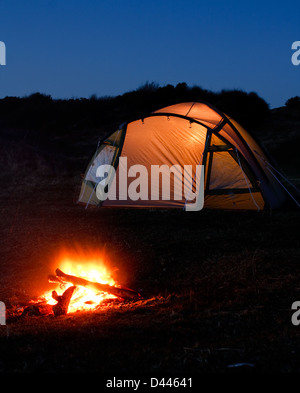Tenda si illumina di notte con il fuoco davanti che simboleggiano vacanza in campeggio o in vacanza nel paese Foto Stock