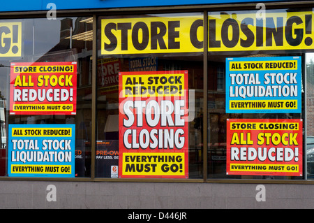 Grandi poster colorati in un High Street negozio finestra annunciando la sua chiusura. Foto Stock