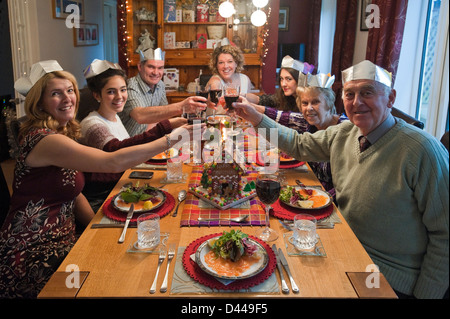 Ritratto orizzontale di tre generazioni di una famiglia godendo il pranzo di Natale insieme attorno al tavolo. Foto Stock