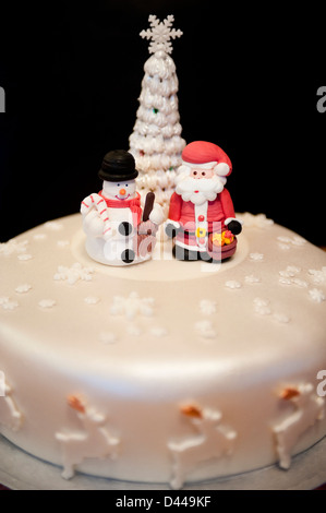 Verticale di chiusura del divertimento modellato figure di Babbo Natale e un pupazzo di neve in piedi su una torta di Natale. Foto Stock
