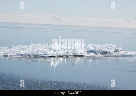 Massa di pezzi di ghiaccio formando una pila su un banco di sabbia in fondali bassi di un grande lago. Foto Stock