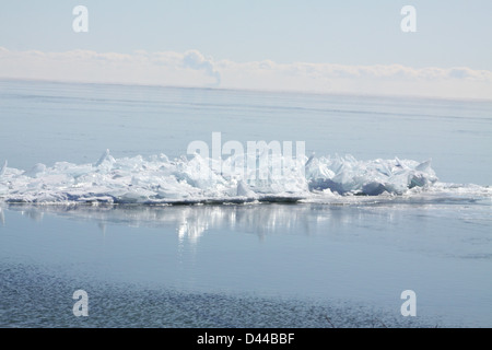 Massa di pezzi di ghiaccio formando una pila su un banco di sabbia in fondali bassi di un grande lago. Foto Stock