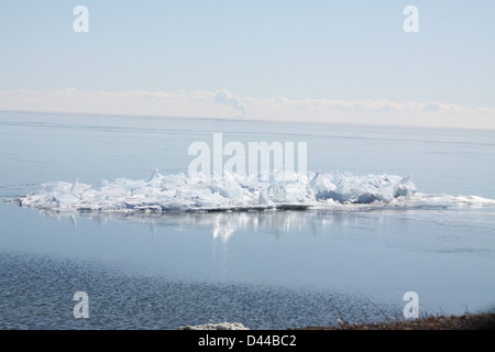 Massa di pezzi di ghiaccio formando una pila su un banco di sabbia in fondali bassi di un grande lago. Foto Stock