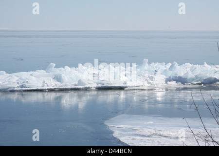 Massa di pezzi di ghiaccio formando una pila su un banco di sabbia in fondali bassi di un grande lago. Foto Stock