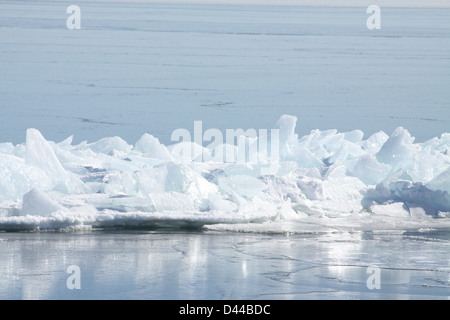 Massa di pezzi di ghiaccio formando una pila su un banco di sabbia in fondali bassi di un grande lago. Foto Stock