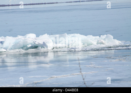 Massa di pezzi di ghiaccio formando una pila su un banco di sabbia in fondali bassi di un grande lago. Foto Stock