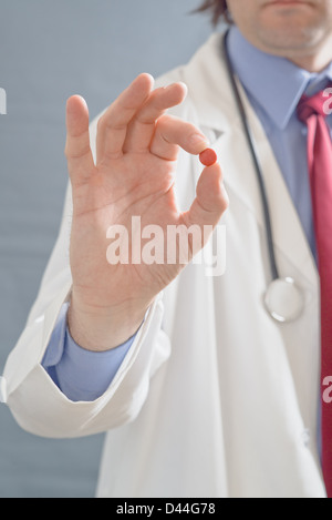 Medico di sesso maschile in possesso di una pillola, chiudere l'immagine con profondità di archiviato con la messa a fuoco a portata di mano con una cura. Foto Stock