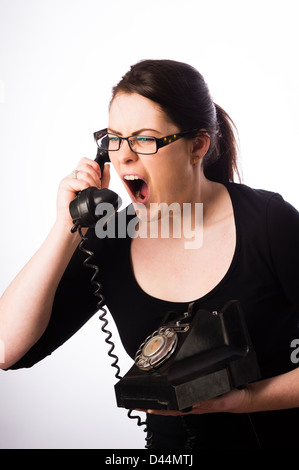 Una giovane donna, marrone capelli, gridando in un vecchio telefono, Regno Unito chiamare help line call center Foto Stock