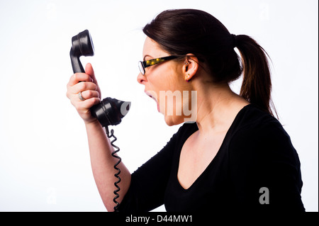 Una giovane donna, marrone capelli, gridando in un vecchio telefono, Regno Unito chiamare help line call center Foto Stock