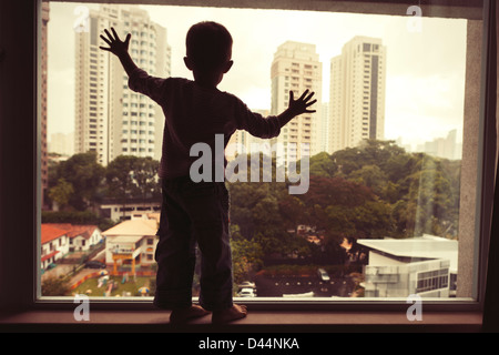 Godendo della vista: boy, finestra, Singapore. Foto Stock