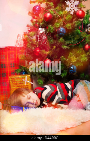 Little Boy si è addormentato sotto albero di Natale Foto Stock