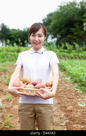 Una donna in una fattoria in posa con un cesto di patate Foto Stock