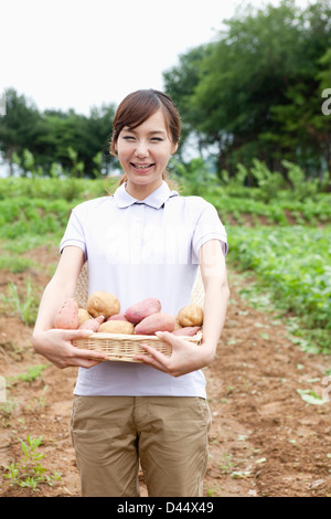 Una donna in una fattoria in posa con un cesto di patate Foto Stock