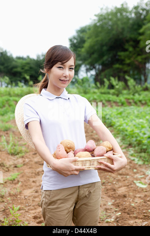 Una donna in una fattoria in posa con un cesto di patate Foto Stock