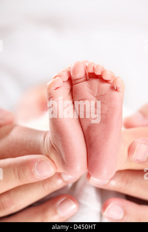 Un genitore che mani teneramente tenere i loro piedi neonato Foto Stock