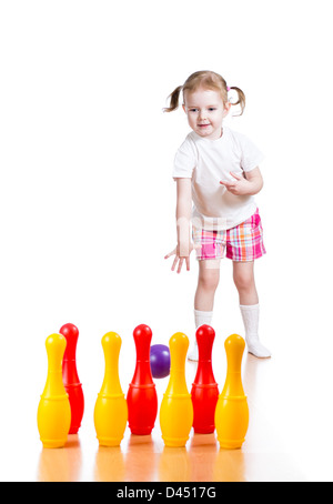 Kid ragazza lanciando la palla a battere giù toy bowling pin. Concentrarsi sul bambino. Foto Stock