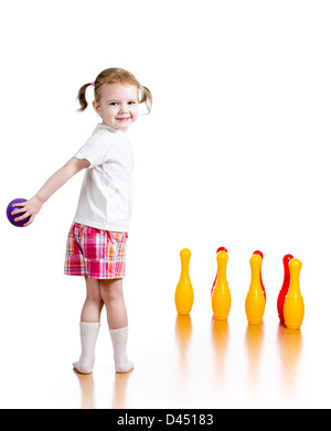 Kid ragazza lanciando la palla a battere giù toy bowling pin. Concentrarsi sul bambino. Foto Stock