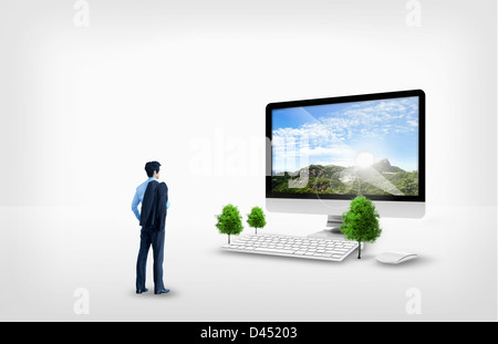 Imprenditore in piedi di fronte a un grande computer Foto Stock