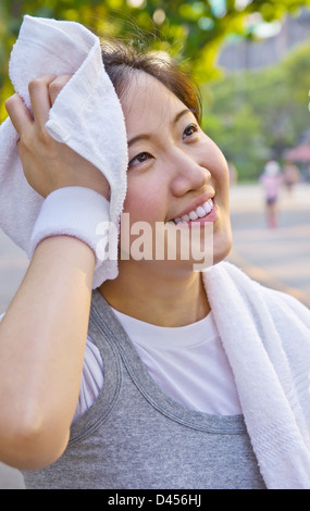 Donna asiatica tergi sudore con un asciugamano dopo esercizio Foto Stock