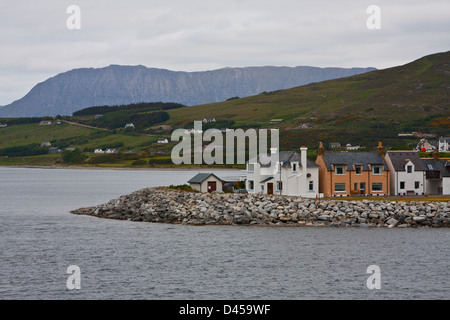 Un lungo spiedo di sabbia che forma il braccio del porto a Ullapool è rivestito con case. Foto Stock