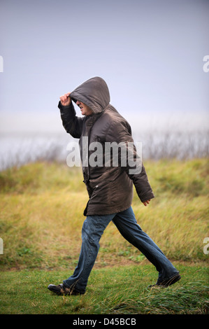 Un uomo insegue il suo cane su un umido giorno ventoso REGNO UNITO Foto Stock