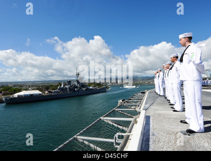 I marinai stand al resto parata come uss nimitz passa la USS Missouri corazzata Memorial e la USS Arizona Memorial nel porto di perla. Foto Stock