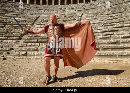 Glowering gladiatore romano con la spada diffusione cape sun sul palco dell'antico teatro di Aspendos in Turchia Foto Stock