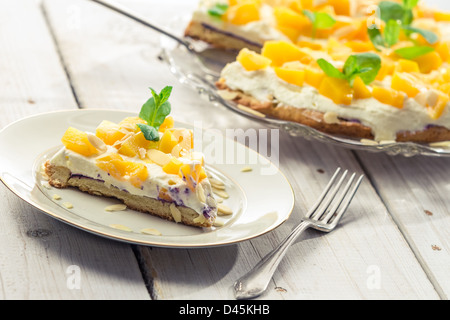 Torta con crema e pesche su una piastra Foto Stock