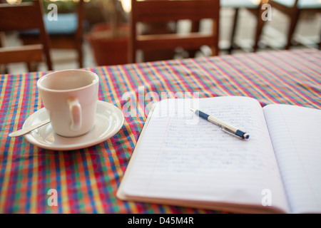 Tenere un diario di un viaggio ufficiale e la tazza di caffè in una tavola in Suchitoto El Salvador Foto Stock