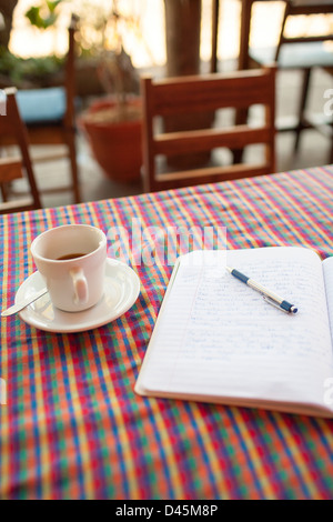 Tenere un diario di un viaggio ufficiale e la tazza di caffè in una tavola in Suchitoto El Salvador Foto Stock