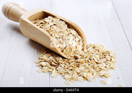 Fiocchi di avena nel convogliatore in legno bianco su sfondo di legno Foto Stock