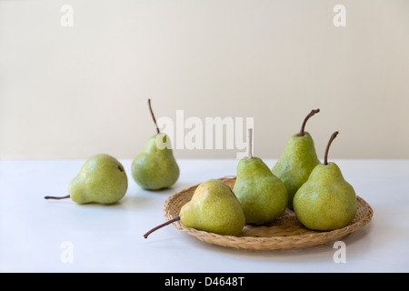 Sei pere verde su un tessuto piatto di rattan e un tavolo bianco top Foto Stock