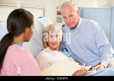 Infermiere parlando di coppia Senior su Ward Foto Stock