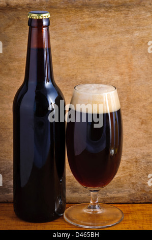 Vetro e bottiglia di birra scura su uno sfondo di legno Foto Stock