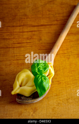 Tortellini fatti in casa e basilico su un cucchiaio di legno Foto Stock