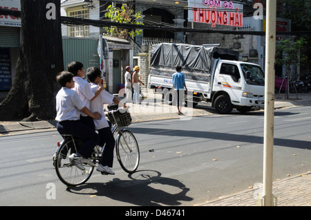 Tre ragazzi su una bicicletta in Ho Chi Minh City in Vietnam Foto Stock