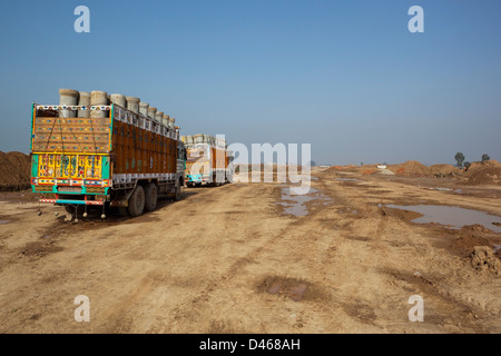 Altamente decorato camion pieni di tubi in attesa su appena azzerato ex terreni agricoli nella periferia di Mohali in Punjab. Foto Stock