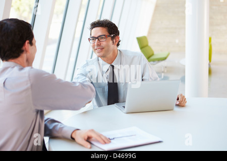 Due imprenditori aventi riuniti intorno al tavolo in ufficio moderno Foto Stock