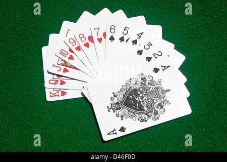 Giocando a carte di cuori e di picche messo streetwise sul tavolo da gioco. Foto Stock