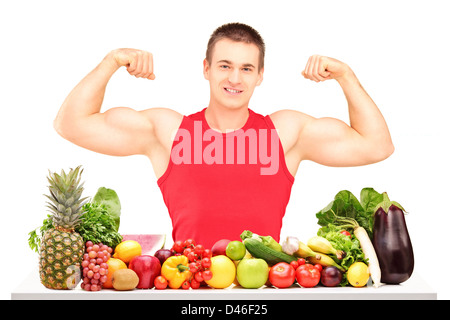 Uomo muscolare in posa con un palo di fatto di frutta e verdura, isolati su sfondo bianco Foto Stock