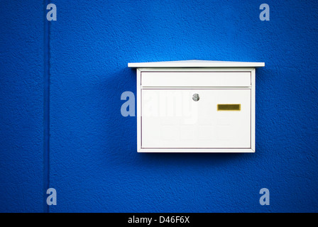 Postbox bianco su una parete blu ,all'aperto Foto Stock