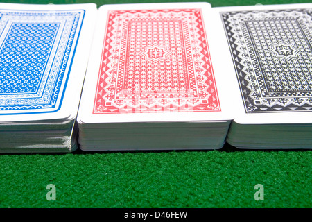 Tre diversi colori di mazzi di carte da gioco sul verde del tavolo da gioco. Foto Stock