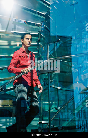 Un giovane latino/modello ispanica salendo una scala in vetro Foto Stock