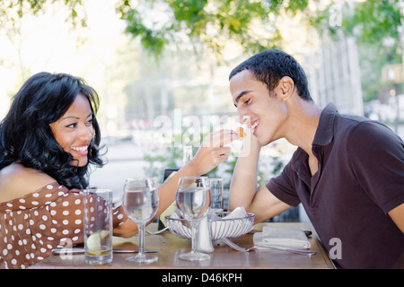 Un amorevole giovane gustando un pasto in un cafè sul marciapiede su un bel giorno Foto Stock