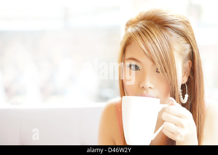 Closeup bella donna seduta al cafe holding e di bere il caffè. Foto Stock