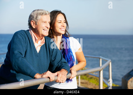 Senior l'uomo con la figlia adulta cercando su parapetto in mare Foto Stock