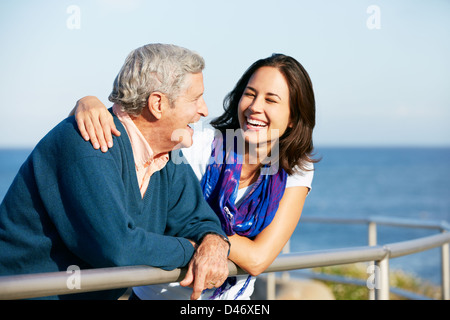 Senior l'uomo con la figlia adulta cercando su parapetto in mare Foto Stock